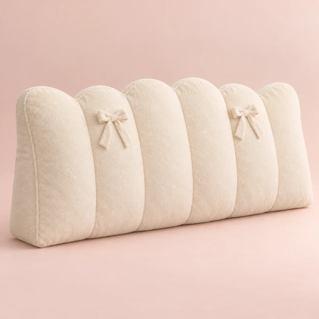 Cloud Ribbon, Cream plush wide bed headboard cushion with scalloped top and two small fixed sewn ribbon bows on upper front, vertical compartment seams